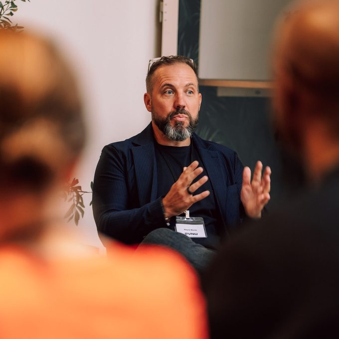 Wayne Morris speaking on a panel, wearing an RVNU badge
